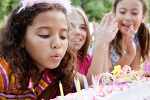 Girl (7-9) blowing out candles on birthday cake